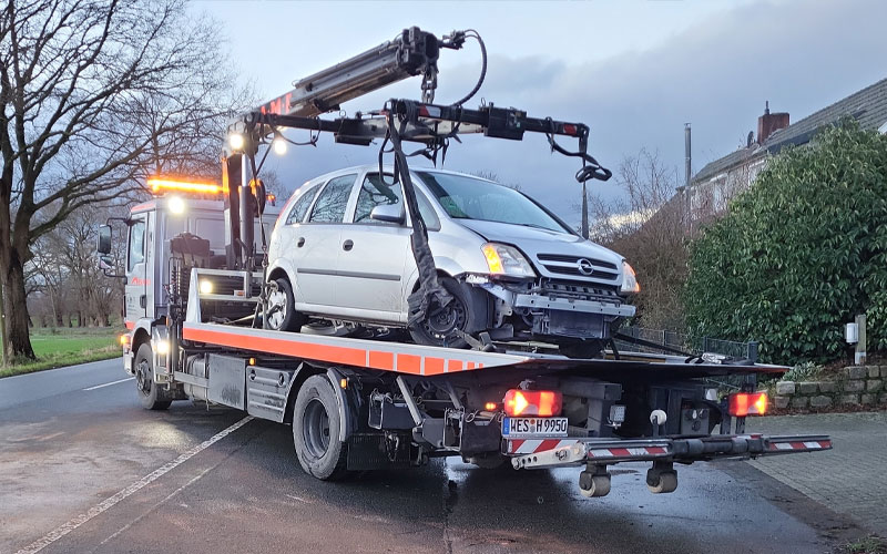 amf-abschleppdienst-b2b-flottenservice-partnerschaft Abschleppwagen von AMF schleppt einen kleinen Opel auf der Ladefläche bei eingeschalteter Beleuchtung ab.