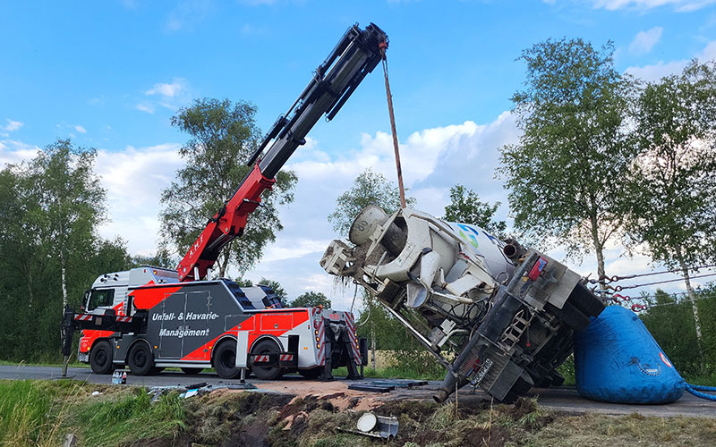 amf-abschleppdienst-bergungsdienst-1 Ein Ladekranfahrzeug von AMF richtet einen Betonmischer auf einer Landstraße auf.