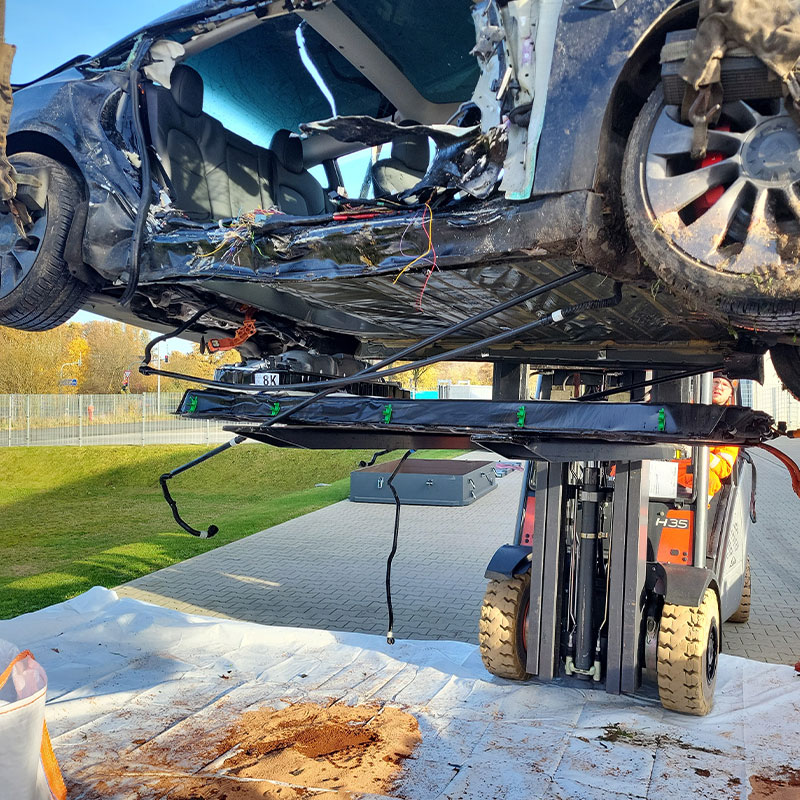 Gabelstapler hebt ein zerstörtes Elektroauto auf dem Firmengelände von AMF hoch.