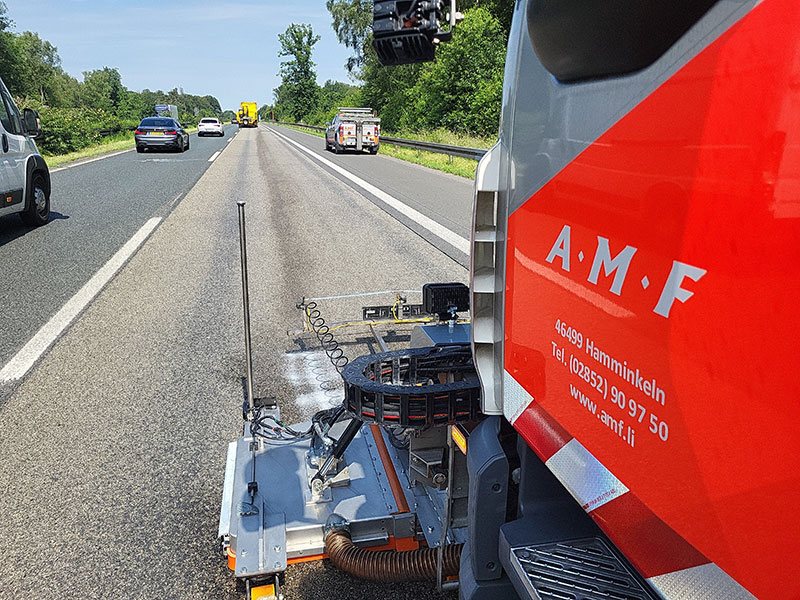 amf-abschleppdienst-nassreinigung Kehrmaschine von AMF reinigt die Autobahn. Davor fahren weitere Fahrzeuge.
